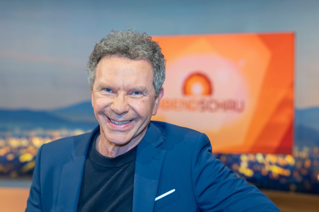 Nahaufnahme von Roman Röll mit dem Abendschau-Schriftzug im Hintergrund