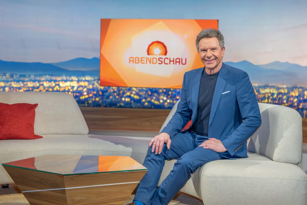Roman Röll sitzt auf dem Sofa im Studio der Abendschau